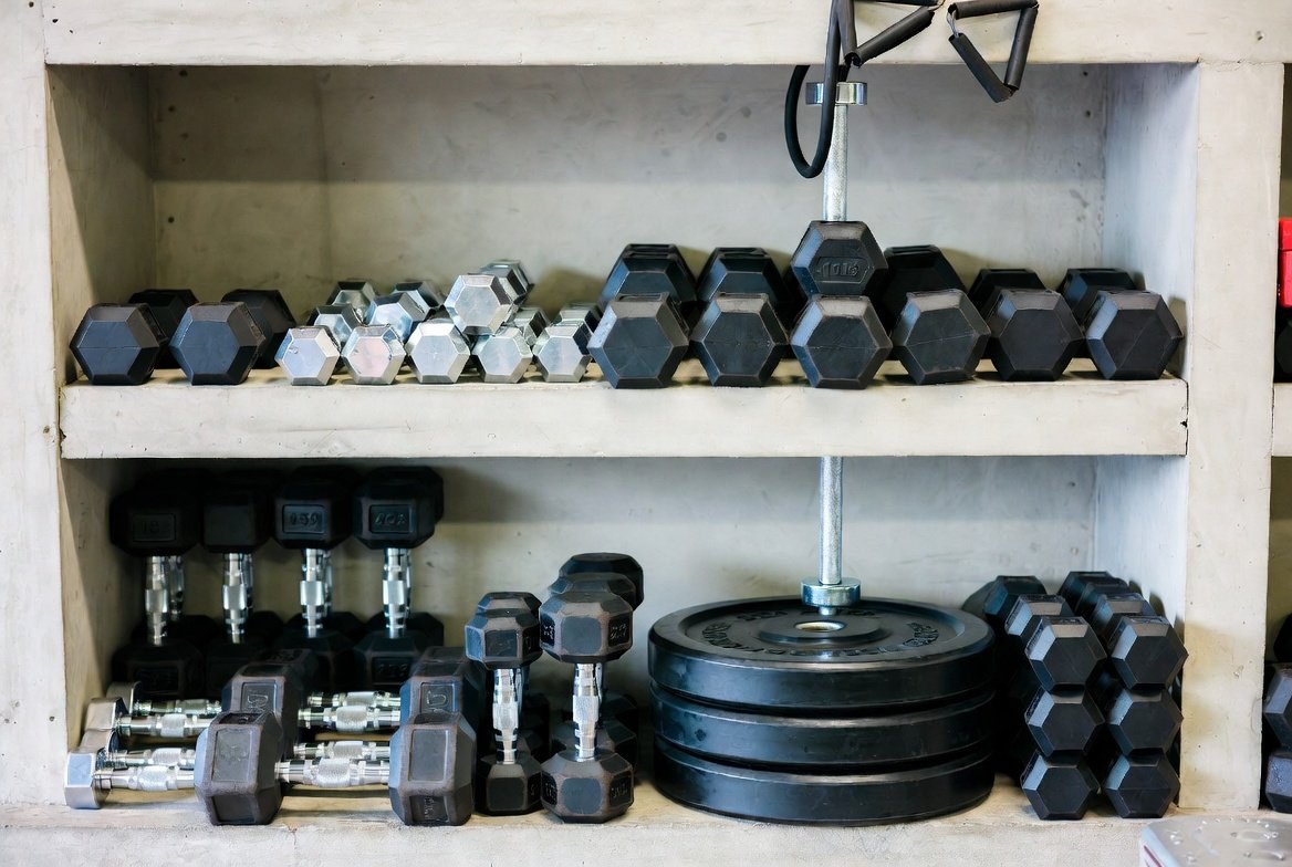Range of fitness equipment including dumbbells and weight plates on a display rack